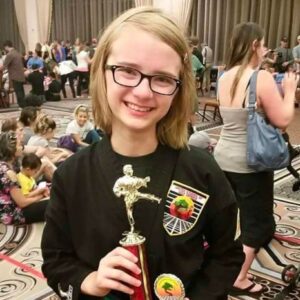 Young student holding trophy, representing confidence built through achievement, practice, and perseverance