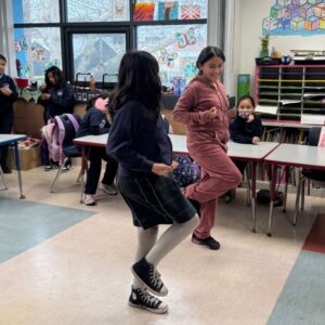 Students performing coordinated movement in classroom, showing confidence and engagement through structured physical activity