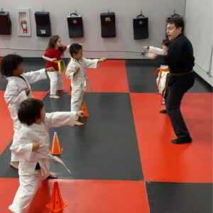 Martial arts instructor leading class of students practicing punches, building confidence through structured group training
